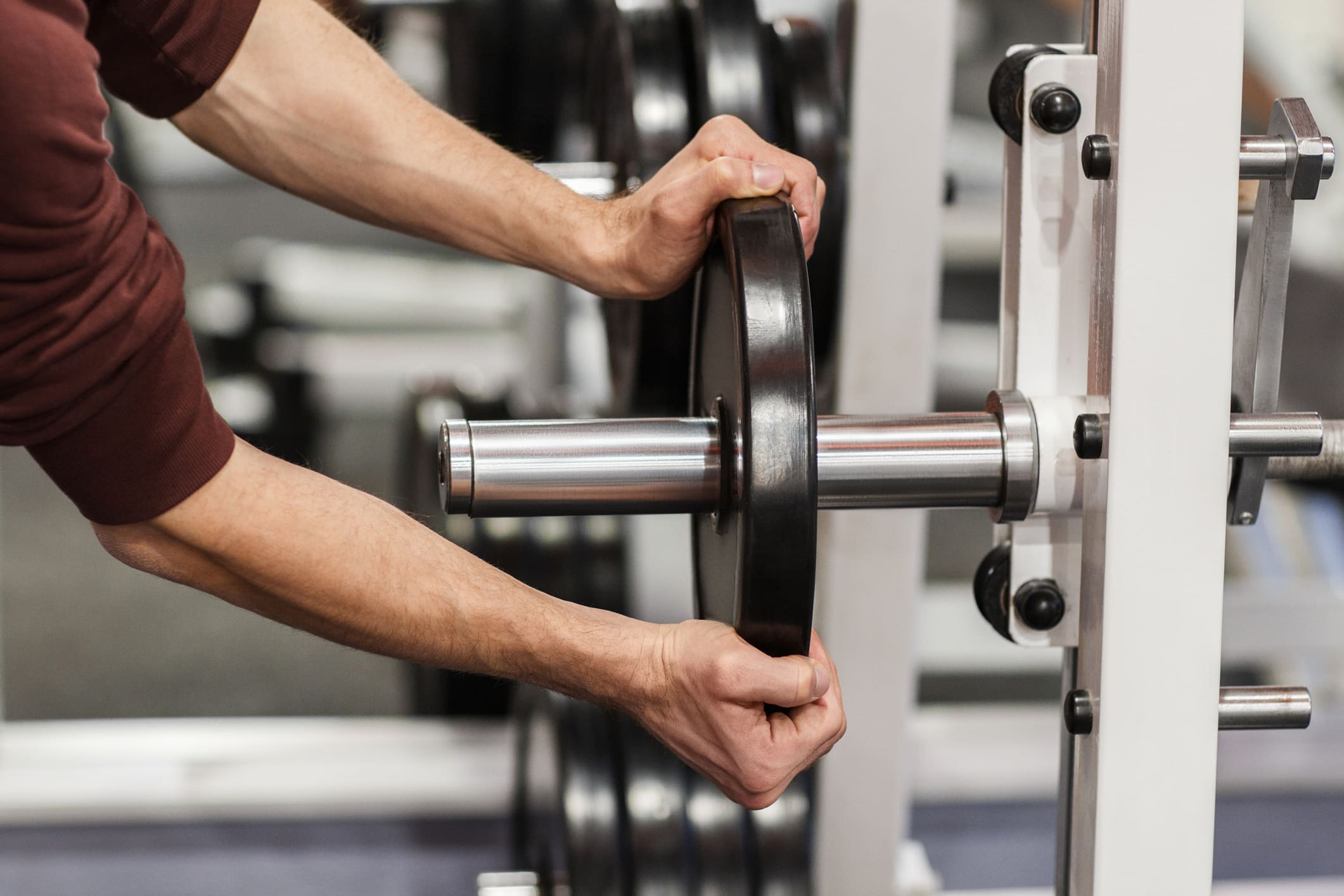 Male hand putting weight plate on barbell
